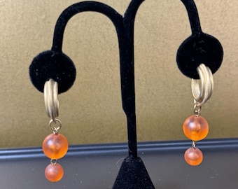 Orange pärlor och guldfärgade metallörhängen med hål i stolpen