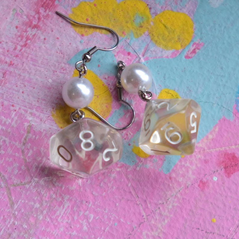 May include: A pair of silver dangle earrings with a clear iridescent dice charm and a white pearl bead on each earring.