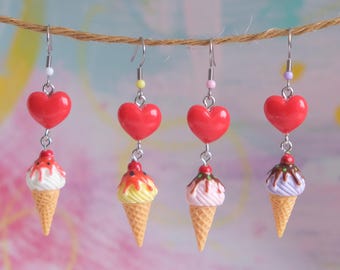 May include: Four pairs of dangle earrings. Each earring features a red heart charm above a miniature ice cream cone. The ice cream cones have different colored scoops and toppings, including red, yellow, pink, and purple.