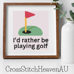 Peut inclure: Modèle de point de croix avec un terrain de golf vert, un drapeau rouge et le texte "J'aimerais mieux jouer au golf".