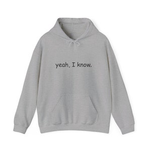 May include: A light gray hoodie with a drawstring hood and a front pocket. The text "yeah, I know." is printed in black across the chest. The hoodie is made of a soft, comfortable material.