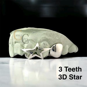 May include: A silver 3-tooth grill with a 3D star design. The grill is displayed on a light green dental mold. The text "3 Teeth 3D Star" is visible in the image.