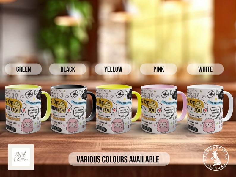 May include: Five mugs with different coloured rims, each featuring a black and white illustration of a teacup with the text "A cup of positivity" and other doodles. The mugs are displayed on a wooden surface with the text "Various colours available" below.