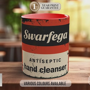 Peut inclure: Mug en céramique avec intérieur rouge et design vieilli. Le mug affiche le mot "Swarfega" en blanc sur une bande noire, avec "ANTISEPTIC hand cleanser" en dessous. Le bas du mug indique "VARIOUS COLOURS AVAILABLE".