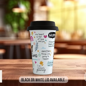 May include: White travel mug with a black lid. The mug has colorful illustrations and text that says "My heart is full of love and joy", "Awesome", "A beautiful day begins with a beautiful mind", "Amazing things are going to happen", "I am constantly growing", and "I am enough and full of joy".