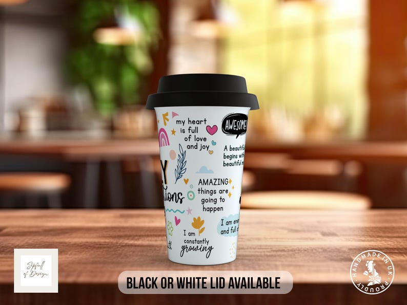 May include: White travel mug with a black lid. The mug has colorful illustrations and text that says "My heart is full of love and joy", "Awesome", "A beautiful day begins with a beautiful mind", "Amazing things are going to happen", "I am constantly growing", and "I am enough and full of joy".