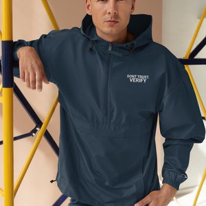 May include: A navy blue windbreaker jacket with a zipper closure and a hood. The jacket has the text "DON'T TRUST. VERIFY." embroidered on the front in white.