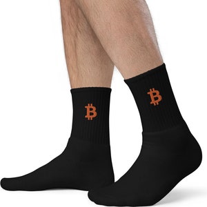 May include: Black crew socks with an embroidered orange Bitcoin symbol on the cuff. The socks are made of a soft material and are designed to be comfortable for everyday wear. The Bitcoin symbol is a recognizable icon.