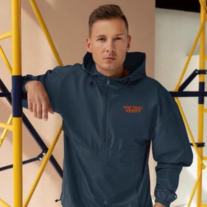 May include: A navy blue hooded jacket with a zipper closure and a kangaroo pocket. The jacket has the text "DON'T TRUST. VERIFY" embroidered on the front in orange.