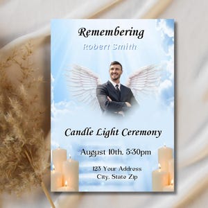 May include: A blue and white memorial card with a photo of a man with angel wings. The card reads "Remembering Robert Smith" and "Candle Light Ceremony August 10th. 5:30pm 123 Your Address City. State Zip".