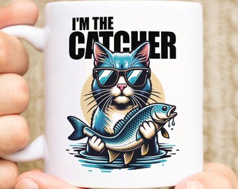 May include: White ceramic mug with a blue cat wearing sunglasses and holding a fish. The text "I'm the Catcher" is printed on the mug.