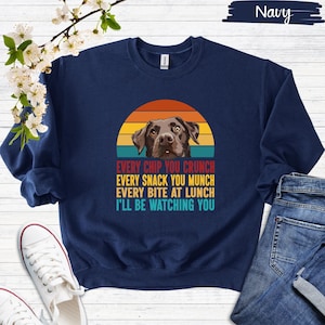 Könnte beinhalten: Marineblauer Sweatshirt mit einem Vintage-Sonnenuntergang-Motiv mit einem Schokoladen-Labrador. Der Text lautet "Every chip you crunch, every snack you munch, every bite at lunch, I'll be watching you."