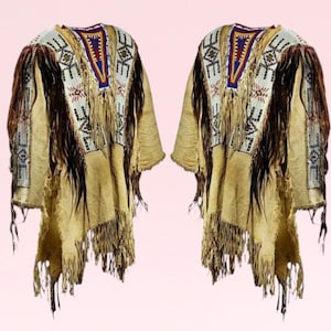 May include: Two identical beige leather jackets with intricate beadwork and fringe detailing. The jackets feature geometric patterns in white, blue, and red beads. The fringe is made of leather and hangs down from the bottom of the jackets.