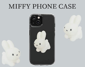 May include: A clear phone case with a white bunny rabbit design. The case has a black background and a clear border. The bunny rabbit is in the center of the case and has a small black nose and eyes.