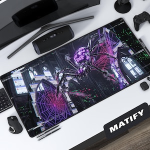 May include: A black rectangular desk mat featuring a detailed illustration of a large, metallic spider with a purple head and glowing web. The background includes gothic architecture and error message windows. The mat is surrounded by computer accessories.