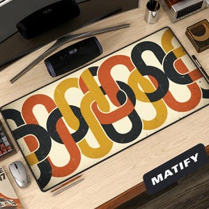May include: A rectangular desk mouse pad with a retro chain link design in black, orange, and yellow on an off-white background. The word "MATIFY" is printed on a black rectangle in the lower right corner. The pad is on a wooden desk.