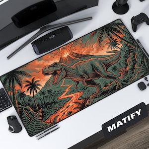 May include: A rectangular desk mat featuring a detailed illustration of a Tyrannosaurus Rex in a prehistoric jungle scene. The design includes a volcano, palm trees, and a river of lava, with a color palette of green, orange, and black.