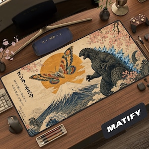May include: A rectangular desk mat featuring a Japanese-style illustration of Godzilla and Mothra against a large yellow sun and Mount Fuji. The design includes cherry blossom branches, ocean waves, and vertical Japanese text in black ink.