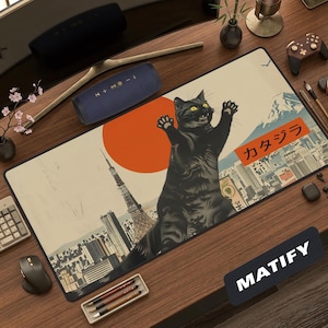 May include: A rectangular desk mat featuring a large black cat standing over a stylized Japanese cityscape with the Tokyo Tower and a large orange sun. The design includes a mountain peak and the Japanese text "カタジラ" in an orange rectangular box.