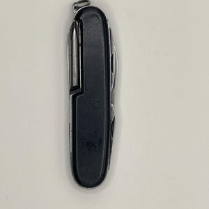 Könnte beinhalten: Ein schwarzes und silbernes Multifunktions-Taschenmesser mit einer Vielzahl von Werkzeugen, darunter eine Klinge, ein Schraubendreher und ein Flaschenöffner.