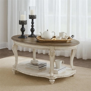 May include: An oval coffee table with a brown wooden top and a distressed white base featuring curved legs and a lower shelf. On the table are two black candle holders with white candles, a wooden tray, a white teapot, and two white mugs.