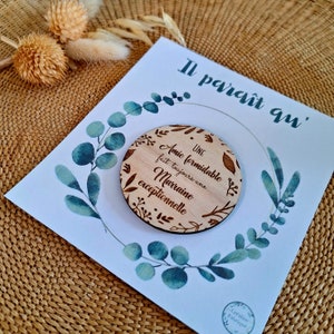 May include: A wooden round sign with a floral design and the text "UNE AMIE FORMIDABLE fait toujours une MARRAINE exceptionnelle". The sign is on a white card with a floral design.