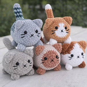 Può includere: Una collezione di cinque giocattoli per gatti fatti a mano all'uncinetto in vari colori. I gatti hanno tratti del viso ricamati e piccole code. I colori includono grigio, arancione, marrone e bianco. I giocattoli sono disposti su una superficie di legno chiaro.