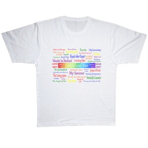 May include: White t-shirt with a rainbow word cloud design featuring religious and spiritual terms like "Alpha and Omega", "Prince of Peace", "True Vine", "Chief Cornerstone", "The Lion of Judah", "Messiah", "Emmanuel", "Son of the Living God", "The King of Kings", "Ehaah Asher Ehayah", "The Light of the World", "Mighty God", "Yahusha' ha Mashiach", "Everlasting Father", "Bright Morning Star", "Lamb of God", "Faithful and True", "Lamb of God", "Joshua the Anointed One", "Melchisedec Priest", "Jesus Christ", "My Savior", "Fountain of Living Waters", "Wonderful Counselor", "The Living Stone", "The Stone the Builders Rejected", "Bread of Life", "The Way, the Truth, the Life", "The Angel of Yah", "Teacher".