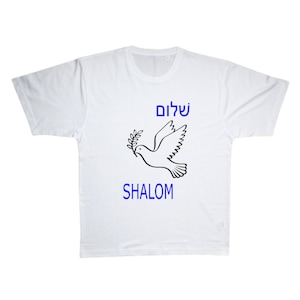 May include: White t-shirt with a black and white illustration of a dove carrying an olive branch. The text "SHALOM" is printed in blue below the dove and the Hebrew word for peace, "שלום", is printed in blue above the dove.
