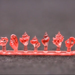 May include: A set of eight red plastic seashells on a red plastic display stand. The seashells are all different shapes and sizes.