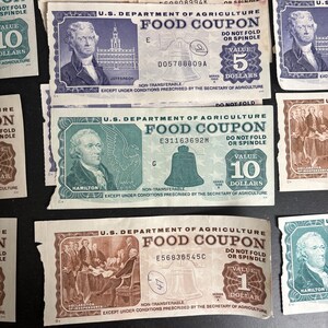 May include: A collection of vintage US Department of Agriculture food coupons. The coupons are printed on green and blue paper with the text "Food Coupon" and the value of the coupon in dollars. The coupons feature images of historical figures such as Jefferson and Hamilton.