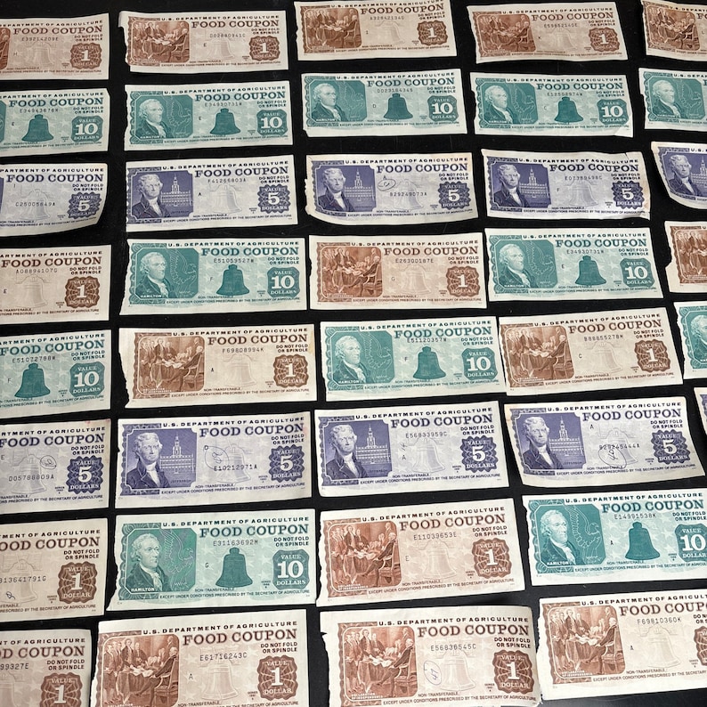 May include: A collection of vintage US Department of Agriculture food coupons. The coupons are printed on green and brown paper with black text. The coupons are for 1, 5, and 10 dollars. The coupons are dated 1942.