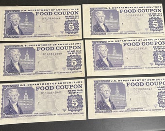 May include: Six vintage US Department of Agriculture food coupons, each worth 5 dollars. The coupons are printed on white paper with blue ink and feature a bell, a building, and a portrait of Thomas Jefferson. The coupons have a serial number and a date.