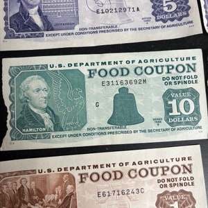 May include: Three vintage food coupons issued by the U.S. Department of Agriculture. The coupons are green, blue, and brown with the text "FOOD COUPON" printed in large letters. The coupons have a value of 5, 10, and 1 dollars, respectively. The coupons are non-transferable and are valid only under conditions prescribed by the Secretary of Agriculture.