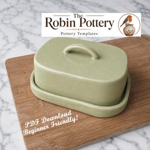 May include: A pale green ceramic butter dish with a lid and handle, on a wooden board. The dish is rectangular with curved edges. The text "The Robin Pottery" and "PDF Download Beginner Friendly!" are visible.