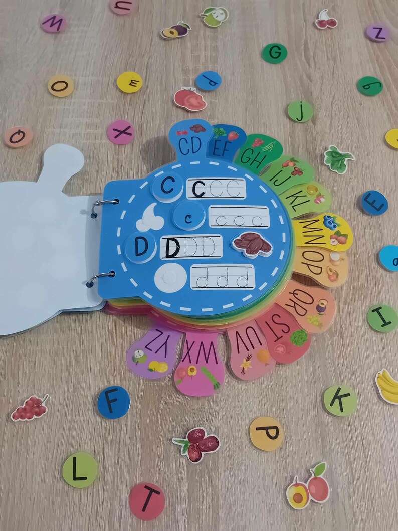 May include: A colorful alphabet learning toy with a blue center and rainbow-colored outer rings. Each ring has a letter and a picture of a fruit or vegetable. The letters are written in uppercase and lowercase. The toy is designed for children to learn the alphabet.