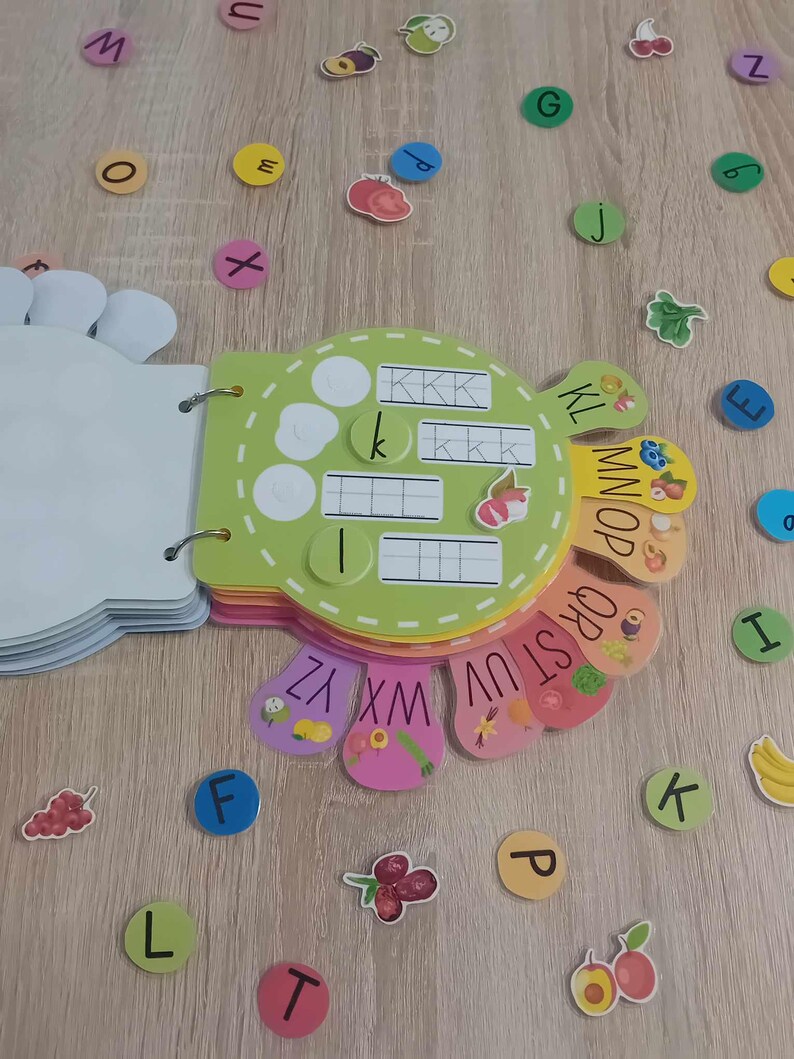 May include: A colorful alphabet learning toy with a green, yellow, and orange base. The toy has a circular shape with different colored sections that feature letters of the alphabet. Each section has a different fruit or vegetable design. The toy is designed for children to learn the alphabet.