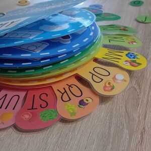 May include: A colorful alphabet learning toy with a rainbow design. Each letter is on a separate piece with a picture of a fruit or vegetable. The letters are arranged in a circle.