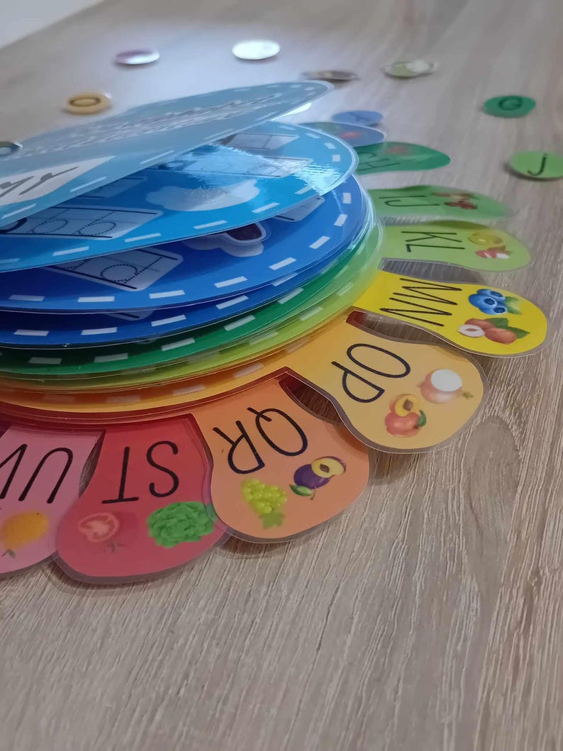 May include: A colorful alphabet learning toy with a rainbow design. Each letter is on a separate piece with a picture of a fruit or vegetable. The letters are arranged in a circle.