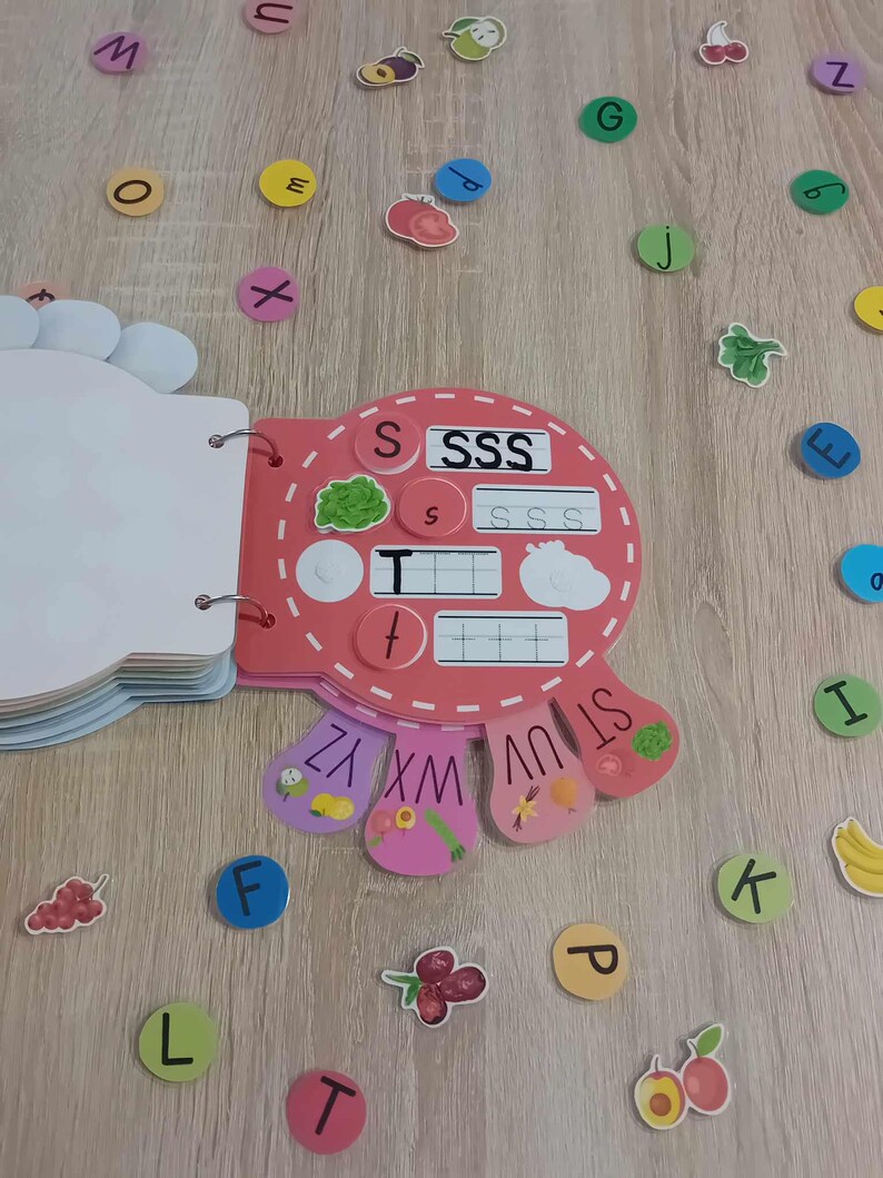 May include: A pink and red alphabet learning toy with a flap book and a spinning wheel with letters S, T, U, V, W, X, Y, and Z. The toy has a section for learning the letter S with the words "SSS" and "SSSS" printed on it.