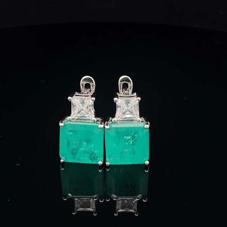 Peut inclure: Une paire de boucles d'oreilles en argent avec des pierres pr&eacute;cieuses carr&eacute;es vertes et des accents de zircone cubique clairs.