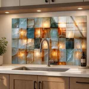 May include: A kitchen backsplash featuring a grid of translucent, square tiles in shades of amber, gold, and cool blue. The tiles have a textured, crystalline appearance with internal light diffusion, positioned behind a stainless steel faucet.