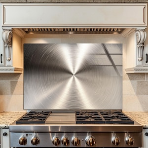 May include: Stainless steel range with a brushed metal backsplash. The kitchen features white cabinets, a granite countertop, and a wooden knife block. The backsplash has a circular pattern design.