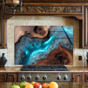 Puede incluir: Un protector contra salpicaduras de cocina con un diseño abstracto vibrante. La obra de arte presenta un río de resina azul turquesa sobre un fondo de veta de madera marrón rica, creando un contraste llamativo. La cocina tiene gabinetes de madera oscura y una estufa de acero inoxidable.