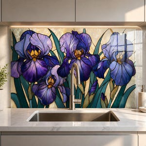 May include: A kitchen backsplash panel featuring a stained glass style illustration of vibrant purple iris flowers with yellow centers and long green leaves against a cream background, positioned behind a stainless steel sink and faucet.