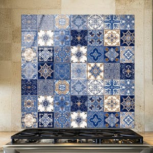 Puede incluir: Un panel de pared cuadrado con una cuadrícula de azulejos decorativos en tonos azul, blanco y bronceado. Cada azulejo muestra un patrón geométrico o floral único, creando un efecto de mosaico. El panel está colocado detrás de una estufa.