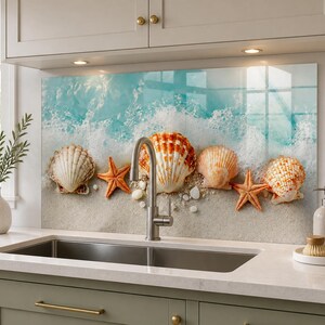 May include: A kitchen backsplash panel featuring a high-resolution print of a sandy beach with white sea foam, orange starfish, and various seashells. The panel is installed behind a stainless steel kitchen faucet and a double basin sink.