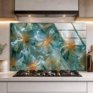 May include: A rectangular glass kitchen backsplash panel featuring a printed design of large, translucent teal and blue flowers with golden-yellow centers and delicate, thin golden stems against a soft, muted green background.