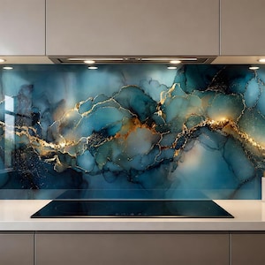 Può includere: Un paraschizzi da cucina caratterizzato da un design astratto fluido nei toni del blu ottanio profondo, blu navy e bianco, accentuato da prominenti venature dorate metallizzate che si estendono orizzontalmente dietro un piano cottura nero.