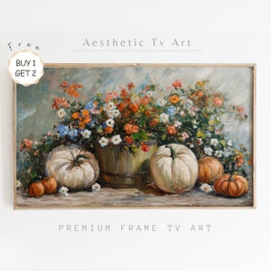 Può includere: Un dipinto incorniciato di una natura morta con zucche e fiori. Le zucche sono bianche e arancioni, e i fiori sono un mix di arancione, rosso, bianco e blu. Il dipinto ha uno sfondo grigio chiaro.